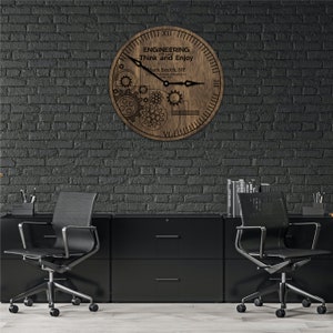 May include: A wooden clock with a gear design and the text "ENGINEERING is a way of life. Think and Enjoy" and "Mark Smith, NY" on the face. The clock is hanging on a black brick wall.