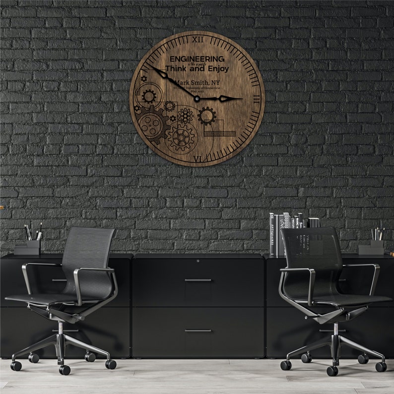 May include: A wooden clock with a gear design and the text "ENGINEERING is a way of life. Think and Enjoy" and "Mark Smith, NY" on the face. The clock is hanging on a black brick wall.