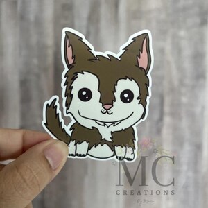 May include: A sticker featuring a cartoon husky with brown and white fur, large black eyes, and a smiling expression. The sticker has a white border and the text "MC CREATIONS" is visible.