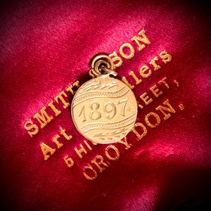 Medallón de amor victoriano «1897» y dije de moneda «D» en oro de 9 quilates; circa 1897