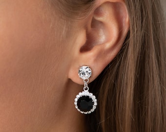 May include: Silver dangle earrings with a black rhinestone surrounded by smaller clear rhinestones.