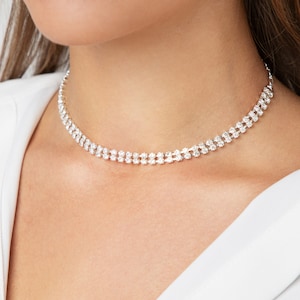 Puede incluir: Un collar choker plateado con dos filas de brillantes transparentes.