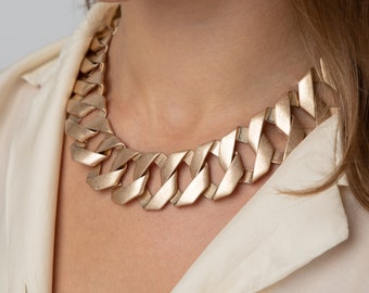 May include: A gold-toned chunky chain necklace with a thick, textured link design.