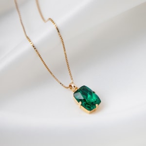 Op de afbeelding: Een gouden ketting met een grote, smaragdgroene edelsteen hanger.