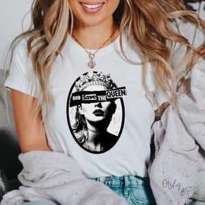 May include: White t-shirt with a black and white graphic of a woman wearing a crown with the text "God Save The Queen" across her eyes.