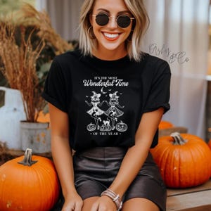May include: Black t-shirt with a white graphic of two witches with pumpkins and the text "It's the most wonderful time of the year."