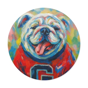 May include: A colorful, round painting of a bulldog wearing a red and blue jersey. The dog's face is painted with vibrant brushstrokes of blue, white, and yellow, with its tongue hanging out. The jersey features a large letter "G".