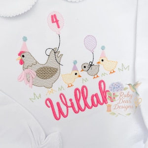 以下が含まれることがあります： 白い長袖シャツ、ピーターパンカラー付き。 鶏、ひよこ、風船の刺繍デザインが特徴です。 「Willah」という名前はピンク色で刺繍されています。「4」の数字はピンク色の風船にあります。