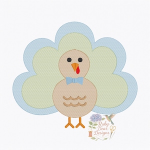 May include: A cartoon turkey design with a light brown body, a blue bow tie, and a red wattle. The turkey's tail feathers are light blue and green. The design is on a white background. The text "Ruby Dear Designs" is in the lower right corner.