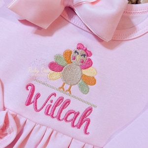 May include: Pink baby dress with an embroidered turkey and the name "Willah" in pink thread.