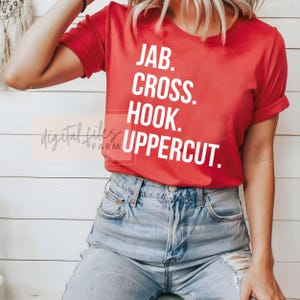 May include: Red t-shirt with white text that reads "JAB. CROSS. HOOK. UPPERCUT."