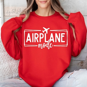 Op de afbeelding: Rood sweatshirt met witte tekst die "AIRPLANE mode" zegt met een klein vliegtuigpictogram boven de tekst.