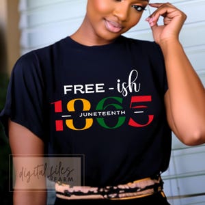 以下が含まれることがあります： 赤、黄、緑の文字で「FREE-ish 1865」と書かれた黒いTシャツ。年の下に「JUNETEENTH」という文字が小さく書かれている。