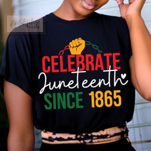 Puede incluir: Una camiseta negra con un diseño gráfico rojo, amarillo y verde. El gráfico presenta un puño levantado liberándose de cadenas, el texto "Celebrate Juneteenth" y el año "1865".