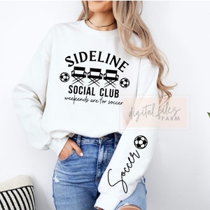 May include: White sweatshirt with black text that reads "Sideline Social Club" with three director's chairs and a soccer ball. The text below reads "weekends are for soccer". The left sleeve has a soccer ball and the word "Soccer" written in cursive.
