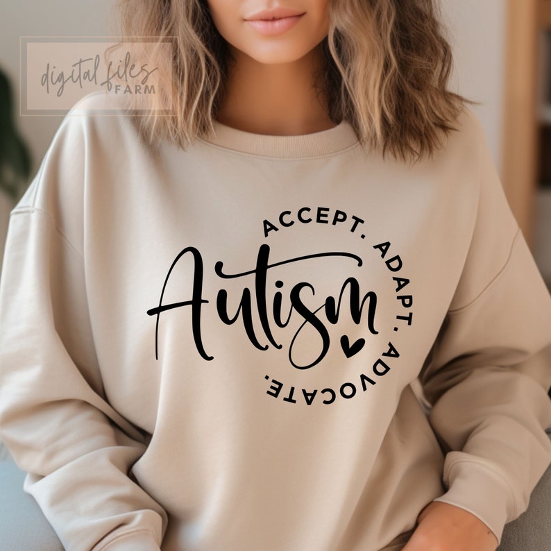 May include: A beige sweatshirt with a black circle graphic that says "ACCEPT. ADAPT. ADVOCATE. Autism" with a small heart symbol.