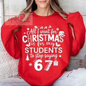 May include: A red sweatshirt featuring the text "All I want for CHRISTMAS is for my STUDENTS to stop saying six 6 seven" in white. The design includes festive Christmas graphics like a Santa hat and snowflakes.