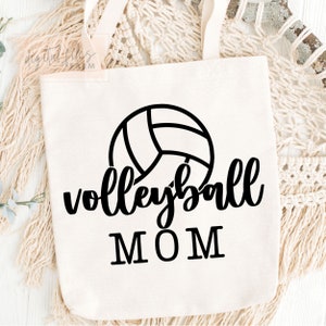 May include: White canvas tote bag with black text and a volleyball graphic. The text reads "volleyball MOM".