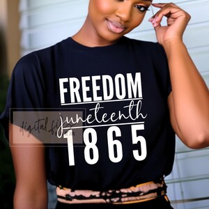 Puede incluir: Camiseta negra con las palabras "FREEDOM juneteenth 1865" en blanco. La camiseta tiene cuello redondo y mangas cortas. El texto está en negrita, sin serifa. La camiseta la lleva una persona.