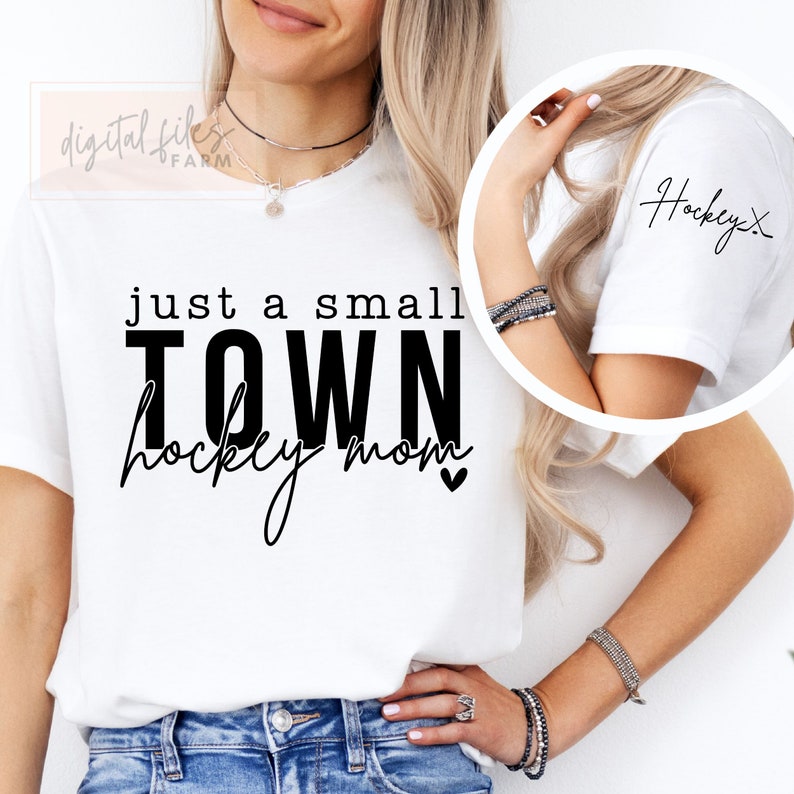 Może przedstawiać: Biała koszulka z czarnym napisem "just a small TOWN hockey mom" z małym symbolem serca. Koszulka ma r&oacute;wnież mały napis "Hockey" na rękawie.