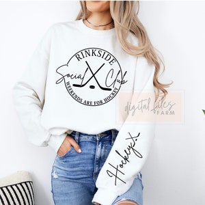 May include: White sweatshirt with a black circle graphic that says "rinkside social club" with hockey sticks and a puck. The text around the circle says "weekends are for hockey". The sleeve of the sweatshirt has the word "hockey" written in cursive.