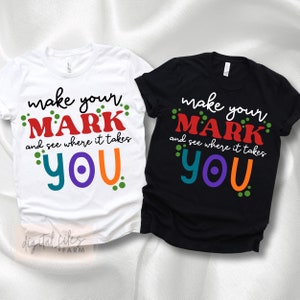 May include: Two t-shirts with the text "make your mark and see where it takes you" in colorful letters and dots. The shirts are white and black.