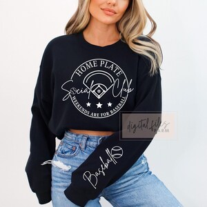 May include: Black cropped sweatshirt with white text that reads "Home Plate Social Club Weekends Are For Baseball". The sweatshirt has a baseball graphic and a baseball on the sleeve.