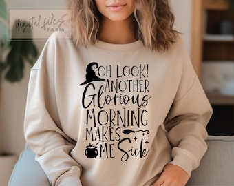 Op de afbeelding: Een beige sweatshirt met een zwarte grafische print die zegt "Oh look! Another glorious morning makes me sick". De grafiek bevat een tovenaarshoed, een ketel en een bezem.