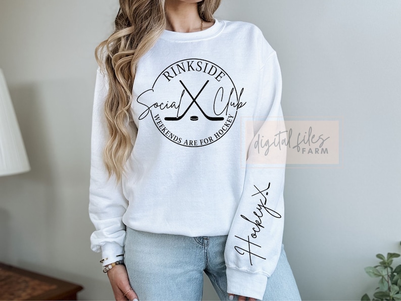 May include: White sweatshirt with a black circle graphic that says "rinkside social club" with hockey sticks crossed inside the circle. The text below the circle says "weekends are for hockey". The left sleeve has the word "hockey" written in cursive.