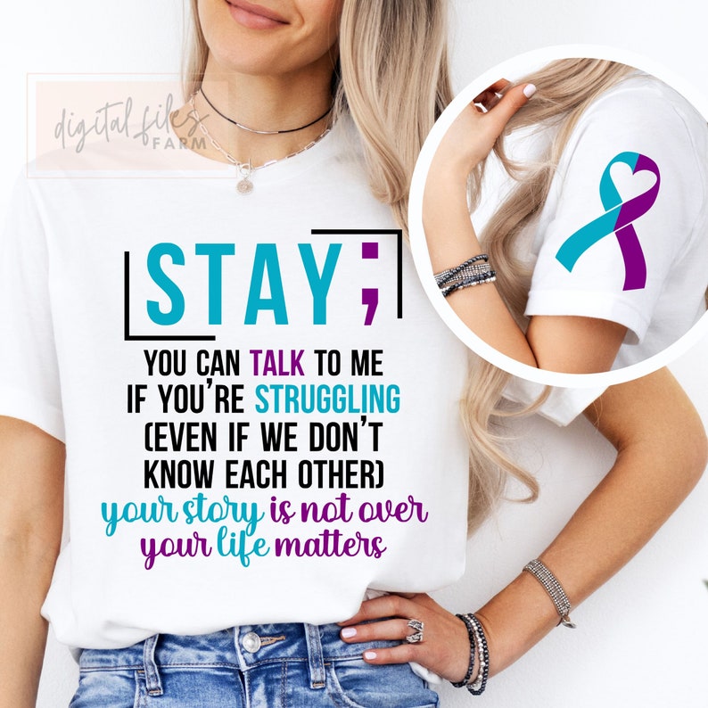 K&ouml;nnte beinhalten: Wei&szlig;es T-Shirt mit dem Text "STAY; YOU CAN TALK TO ME IF YOU'RE STRUGGLING (EVEN IF WE DON'T KNOW EACH OTHER) your story is not over your life matters". Das Shirt zeigt au&szlig;erdem ein t&uuml;rkisfarbenes und violettes Band mit einem Herz in der Mitte.