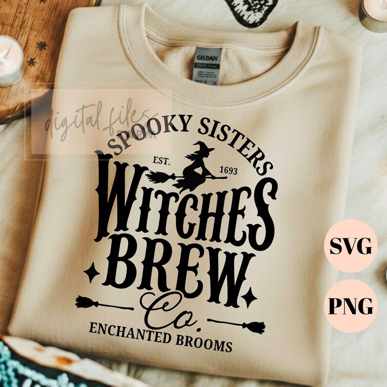 Pu&ograve; includere: Una felpa girocollo color beige con una stampa grafica nera che recita Spooky Sisters Est. 1693 Witches Brew Co. Enchanted Brooms. Il design include la sagoma di una strega su una scopa, piccole stelle e due icone di scope.