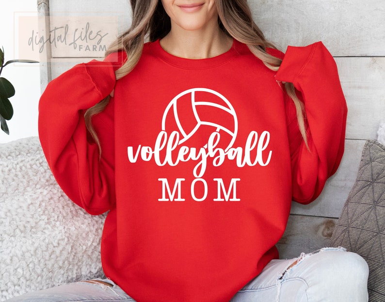 May include: Red sweatshirt with white text and a volleyball graphic that says "volleyball MOM".