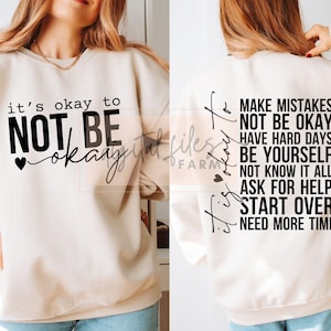 以下が含まれることがあります： クリーム色のスウェットシャツで、黒い文字で「it's okay to NOT BE okay」と前面に書かれており、背面には「it's okay to MAKE MISTAKES NOT BE OKAY HAVE HARD DAYS BE YOURSELF NOT KNOW IT ALL ASK FOR HELP START OVER NEED MORE TIME」と書いてあります。
