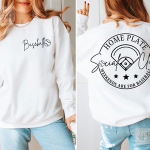 May include: White sweatshirt with black text and a baseball graphic on the front. The back of the sweatshirt has a black circle with the text "Home Plate Social Club" and "Weekends Are For Baseball" around the circle.