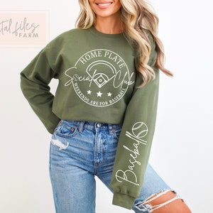 May include: A green sweatshirt with a white graphic that says "Home Plate Social Club" with a baseball and stars. The sleeve has a white graphic that says "Baseball" with a baseball.