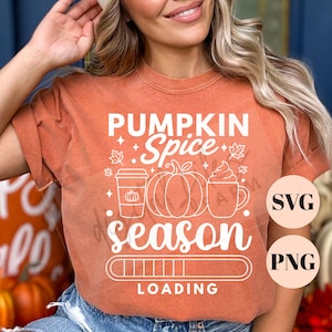 May include: A burnt orange t-shirt featuring white text that reads PUMPKIN SPICE season LOADING. The graphic includes a coffee cup, a pumpkin, and a mug with whipped cream, along with a loading bar graphic and small leaf and star accents.