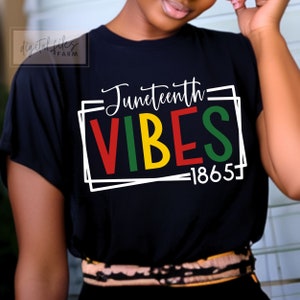 May include: Black t-shirt with a white box around the text "Juneteenth Vibes 1865". The text is in red, green, yellow, and black.