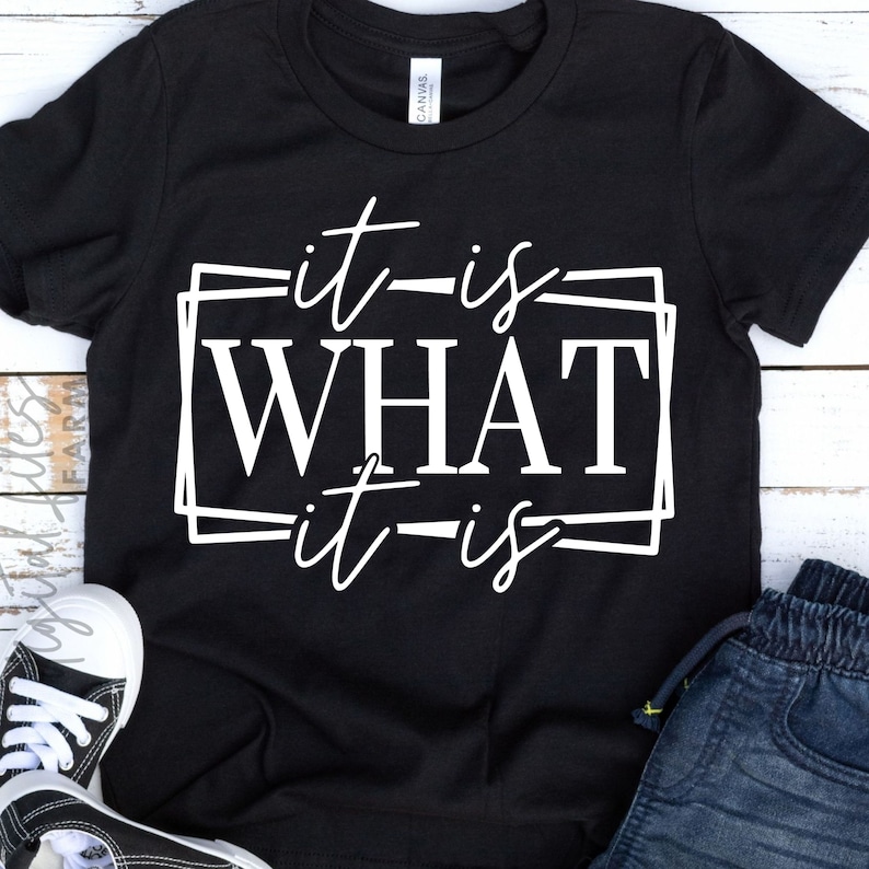 May include: Black t-shirt with white text that reads "it is WHAT it is" in a double-lined box.
