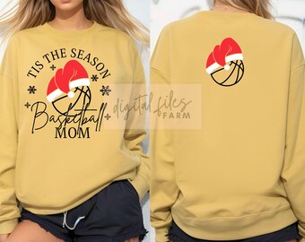 Puede incluir: Una sudadera amarilla con el texto "Tis the Season Basketball Mom" y una pelota de baloncesto con un gorro de Papá Noel. La parte posterior de la sudadera tiene una pelota de baloncesto con un gorro de Papá Noel.