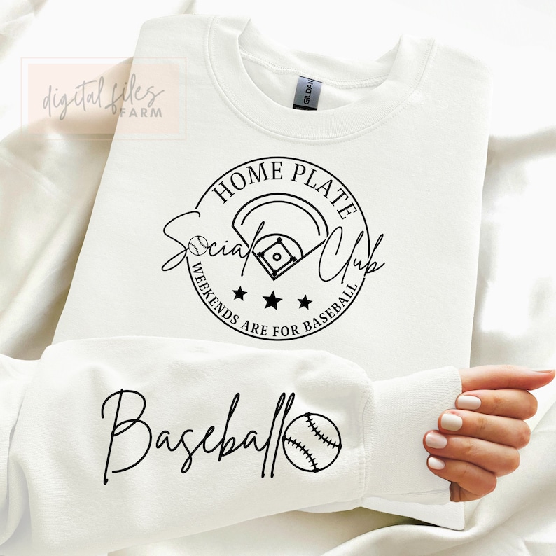 May include: White sweatshirt with a black graphic design that says "Home Plate Social Club Weekends Are For Baseball" with a baseball diamond and three stars. The bottom of the sweatshirt has a black graphic design that says "Baseball" with a baseball.