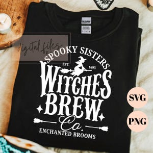 Pu&ograve; includere: Una t-shirt nera con una stampa grafica bianca che recita Spooky Sisters Witches Brew Co. Est. 1693 Enchanted Brooms. Il design include la sagoma di una strega su una scopa, stelle e icone di scope. La maglietta presenta un'etichetta Gildan.