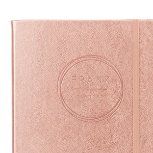 May include: A rose gold planner with the text "FRANK PLANNER" embossed in a circle on the front cover.