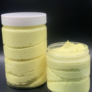 Puede incluir: Dos frascos de plástico transparente llenos de un producto amarillo batido. El frasco más grande tiene una tapa blanca y el frasco más pequeño está abierto. El producto tiene una apariencia en capas y el fondo es negro.