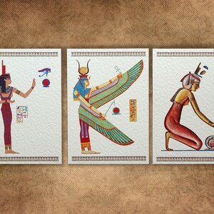 May include: Three framed illustrations of Egyptian goddesses. The first goddess is standing with her arms outstretched, wearing a red dress and a blue headdress. The second goddess is standing with her wings spread, wearing a green dress and a blue headdress. The third goddess is kneeling, wearing a red dress and a blue headdress.