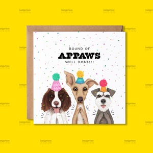 May include: A square greeting card featuring three dogs wearing colourful party hats against a white background with confetti. The text reads ROUND OF APPAWS WELL DONE!!! The dogs are a brown and white spaniel, a tan greyhound, and a grey schnauzer.