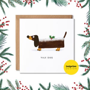 May include: A Christmas card featuring a brown and white dachshund with a holly sprig on top. The card has the text "Yule Dog" and "badgerbee DESIGN" on it.