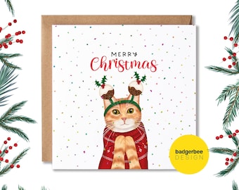 May include: A Christmas card featuring a cartoon orange cat wearing a red sweater and a festive hat with two Christmas pudding toppers. The card has a white background with colorful confetti and the text "Merry Christmas".