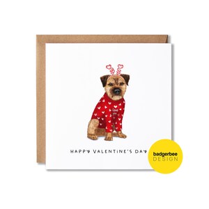May include: A Valentine's Day card featuring a brown and white dog wearing a red sweater with white hearts and a pink heart headband. The card reads "Happy Valentine's Day" and has a yellow circle with the text "badgerbee DESIGN".