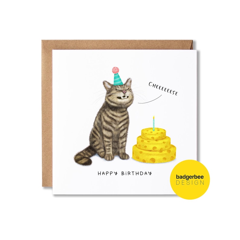 May include: A birthday card with a cartoon cat wearing a party hat, a three-tiered yellow cake with a lit candle, and the words "Cheeeeeese". The card also says "Happy Birthday".