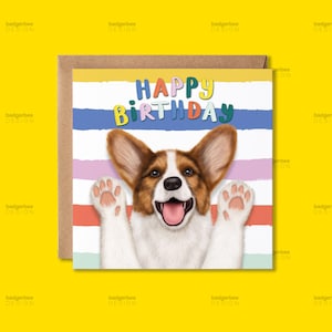 Op de afbeelding: Een vierkante wenskaart met een bruin-witte Corgi met grote oren en opgeheven poten, tegen een achtergrond van horizontale pastelkleurige strepen. De tekst "HAPPY BIRTHDAY" staat in kleurrijke, speelse letters boven de kop van de hond.